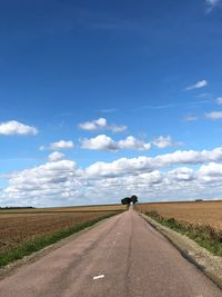 Road amidst field against sky