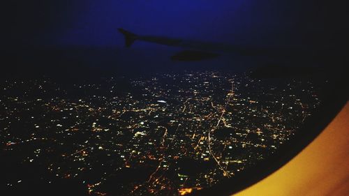 Close-up of illuminated airplane wing against sky at night