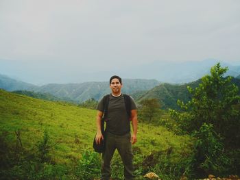 Portrait of smiling man standing on landscape against sky