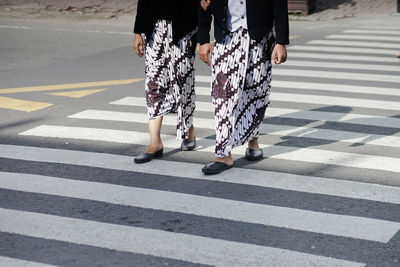Low section of people walking on zebra crossing