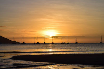 Distance shot of boats in calm sea at sunset