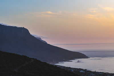 Scenic view of cliffs and sea against sky during sunset