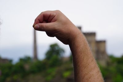 Cropped hand of man against sky