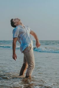 Full length of happy boy on beach against sky