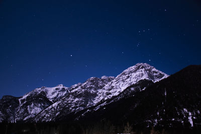 Scenic view of snowcapped mountains against blue sky at night