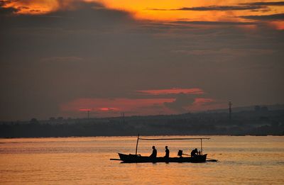 People traveling in boat during sunset