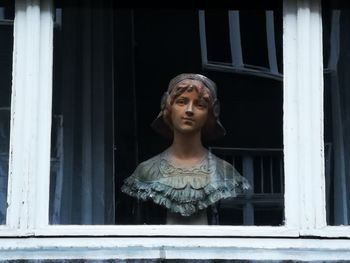 Portrait of woman standing against window