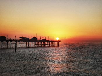 Silhouette pier over sea against sky during sunset