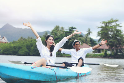 Happy friends enjoying in boat against sky