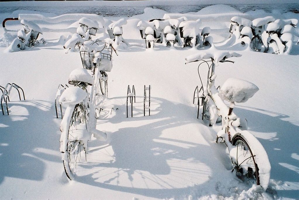 transportation, mode of transport, land vehicle, bicycle, stationary, street, parking, parked, travel, road, day, snow, incidental people, white color, sunlight, winter, car, shadow, outdoors, parking lot
