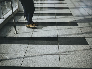 Low section of person standing on floor at railroad station