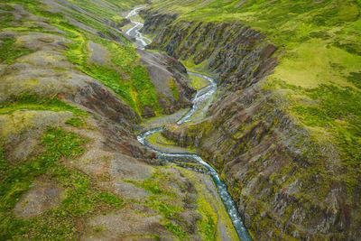 Drone view over green hills, canyon and small river in iceland, summertime.