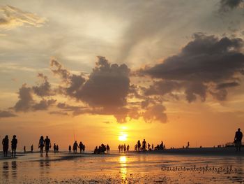 Silhouette people on beach against sky during sunset