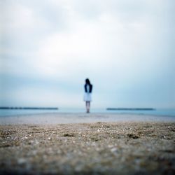 Woman standing at beach against sky