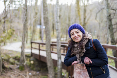 Portrait of woman leaning on footbridge during winter