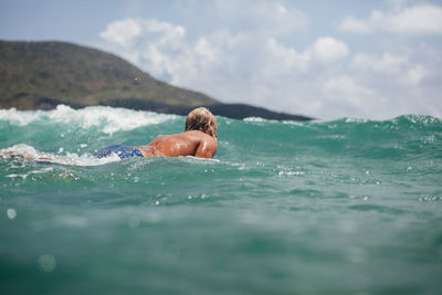 Man swimming in sea against sky