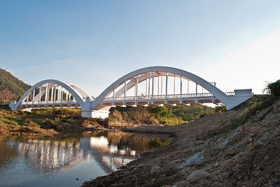 White railway bridge over river against sky