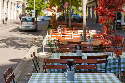 Chairs and tables at sidewalk cafe in city