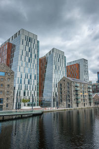Buildings by river against sky