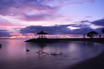 Silhouette built structure by sea against sky during sunset