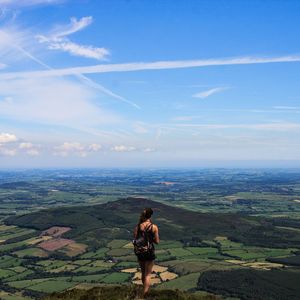 Rear view of man standing on landscape against sky