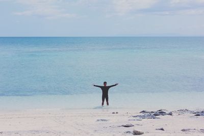 Woman standing on beach by sea against sky