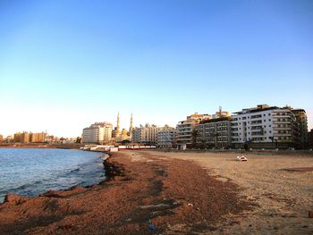 Sea and buildings against clear blue sky