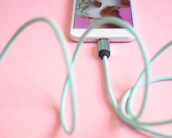 Close-up of smart phone and headphones on pink background