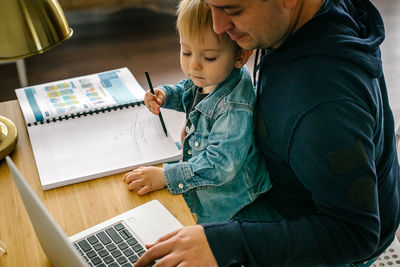 Side view of man using laptop while sitting at home