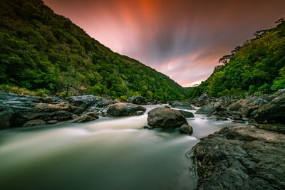 Scenic view of waterfall against sky at sunset