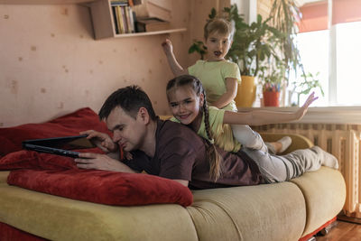 Rear view of father and girl using mobile phone at home