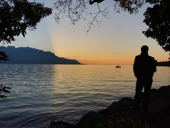 Silhouette man standing by sea against sky during sunset