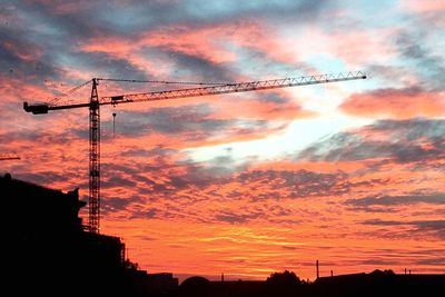 Low angle view of crane against cloudy sky