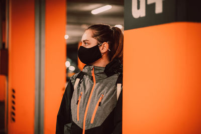 Young woman standing against orange wall