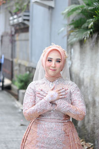 Javanese bride in a beautiful patterned dress and henna in her hand in a wedding party