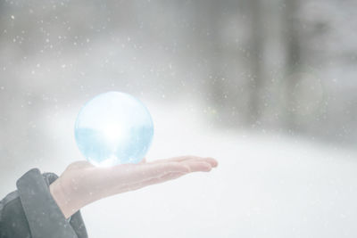 Cropped hand of person holding crystal ball