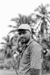 Side view portrait of young man standing against trees