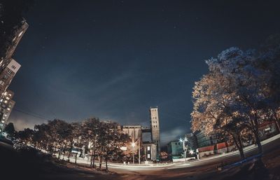 Road by trees against sky in city at night