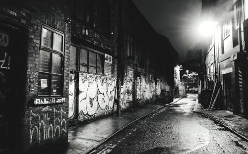 Wet street amidst buildings in city at night