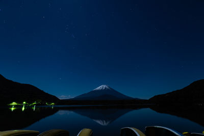Scenic view of lake and snowcapped volcano against sky at night