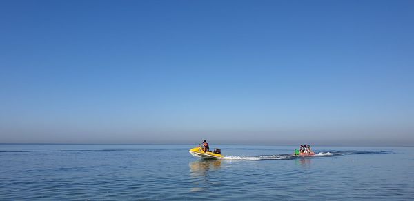 People on sea against clear sky