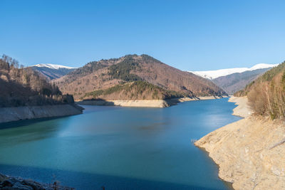 Scenic view of lake and mountains against clear blue sky