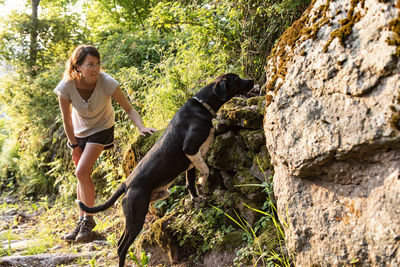 Woman petting and playing with her dog in a forest.