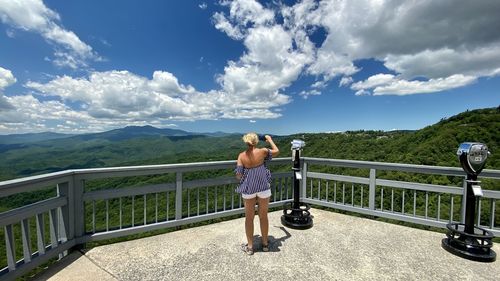 Full length of woman standing on railing against mountains