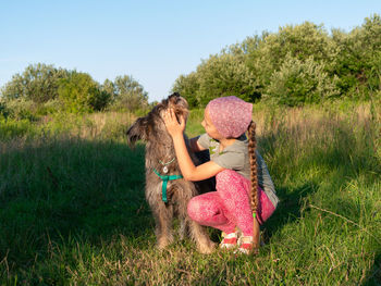 Little girl hugging playing with dog walking spending time together. child with pet in summer meadow