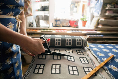 Midsection of woman cutting fabric swatch in shop