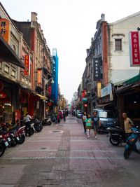 People on street in city against sky