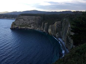 Scenic view of sea by mountains against sky