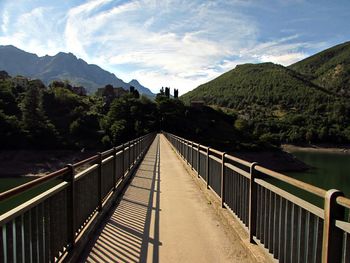 Footbridge amidst mountains against sky