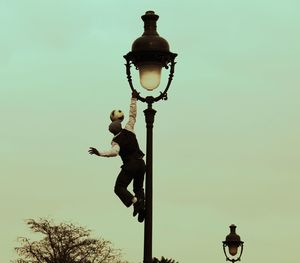 Low angle view of man in street light against sky